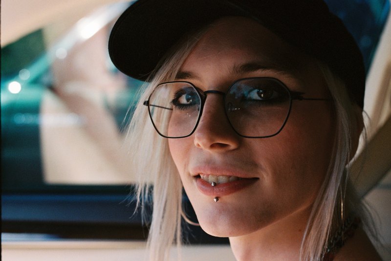 A close portrait of a person wearing glasses and a black cap.